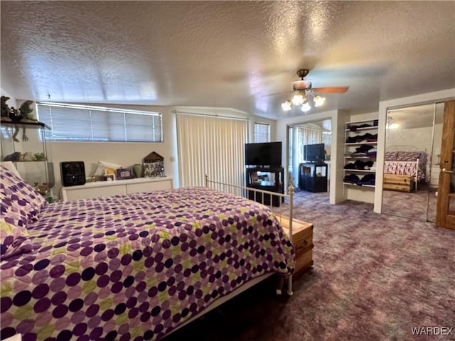 bedroom featuring a ceiling fan, carpet, a textured ceiling, and two closets