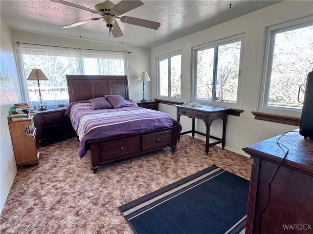 bedroom featuring ceiling fan, a textured ceiling, and light colored carpet