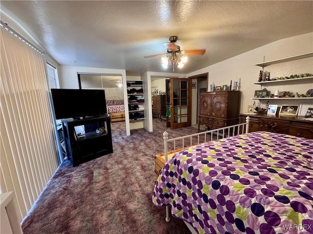 carpeted bedroom featuring a textured ceiling, ceiling fan, and multiple closets