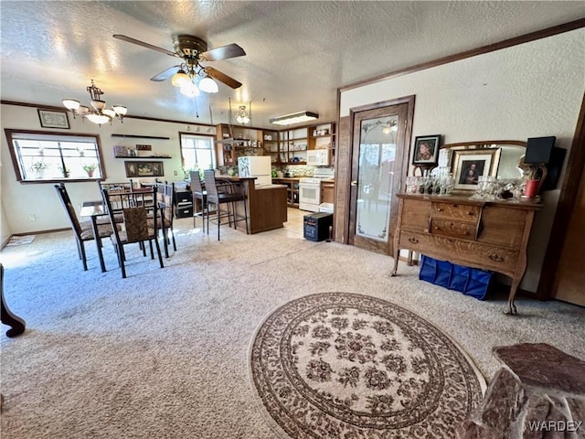 dining space featuring light carpet, a textured wall, ornamental molding, a textured ceiling, and ceiling fan with notable chandelier