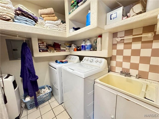 washroom with laundry area, a sink, washing machine and clothes dryer, and light tile patterned floors