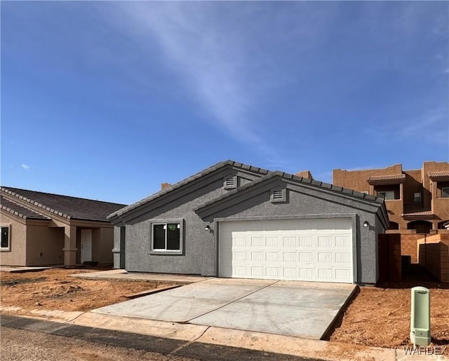 ranch-style home featuring an attached garage, concrete driveway, and stucco siding