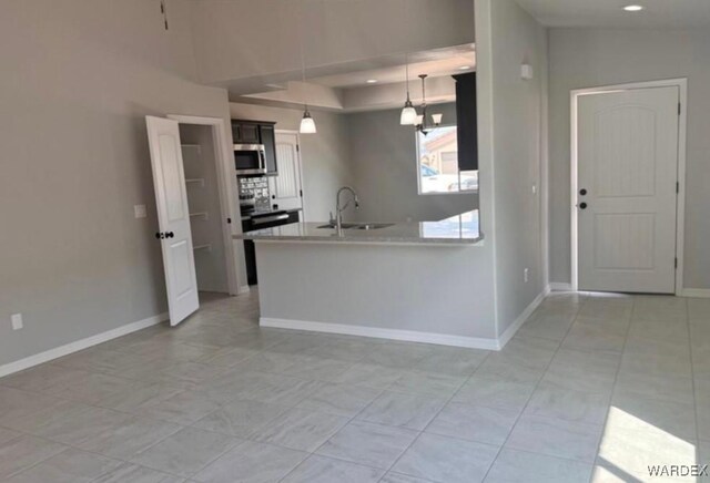 kitchen featuring a peninsula, a sink, hanging light fixtures, light countertops, and stainless steel microwave