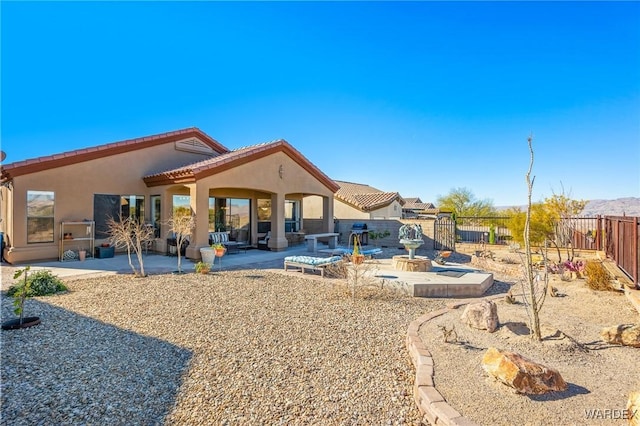 rear view of property with a tiled roof, a patio area, a fenced backyard, and stucco siding