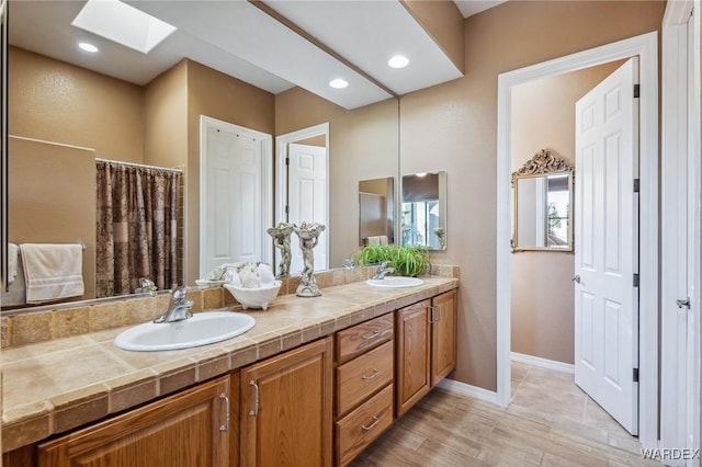 bathroom with a skylight, a sink, and double vanity