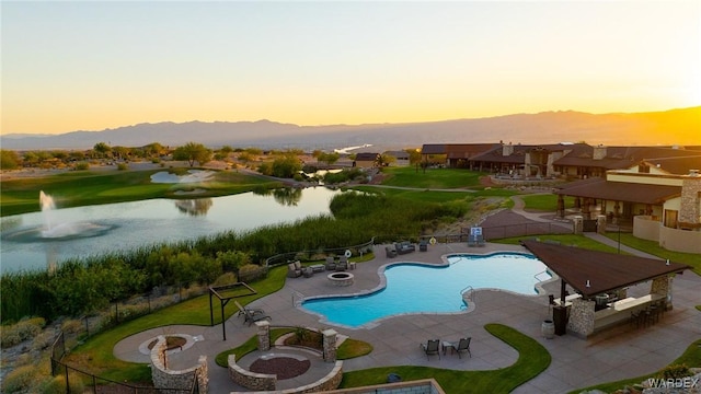 pool at dusk featuring a gazebo, an outdoor bar, fence, and a water and mountain view