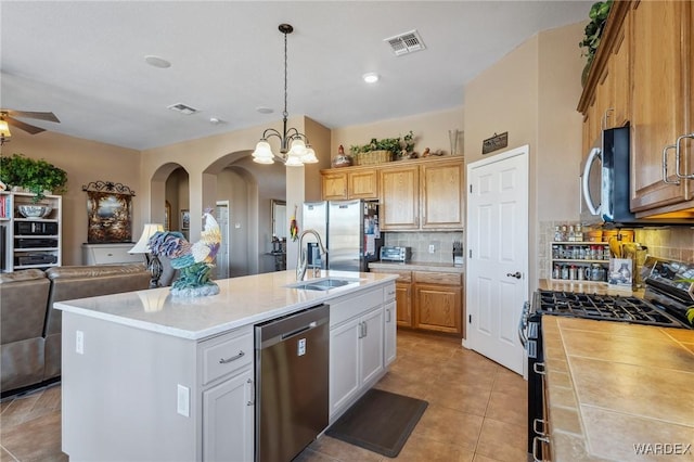 kitchen with white cabinets, open floor plan, light countertops, appliances with stainless steel finishes, and an island with sink