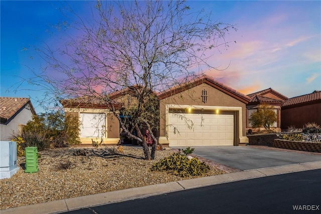 view of front facade featuring an attached garage, a tile roof, concrete driveway, and stucco siding