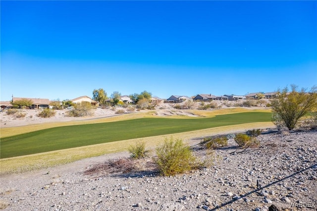 view of community featuring view of golf course and a yard