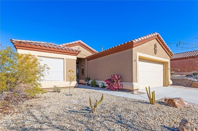 mediterranean / spanish-style house with driveway, an attached garage, a tiled roof, and stucco siding