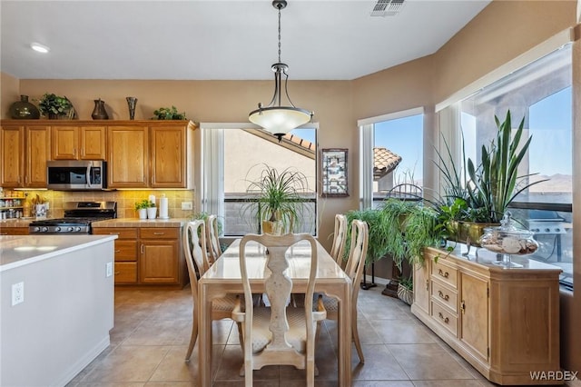 kitchen featuring decorative light fixtures, stainless steel appliances, visible vents, light countertops, and decorative backsplash