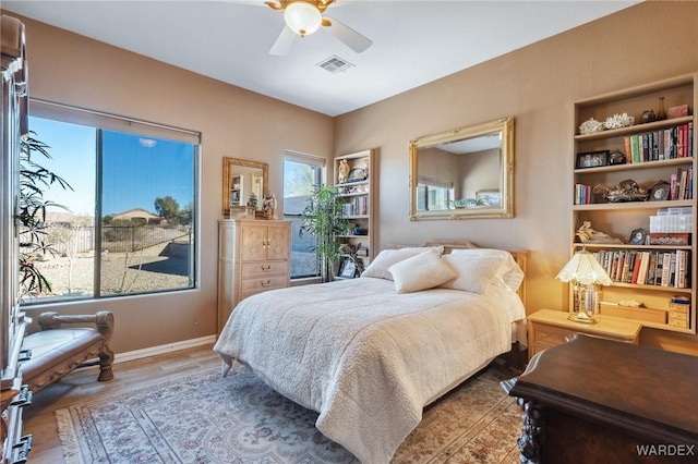 bedroom with visible vents, ceiling fan, baseboards, and wood finished floors