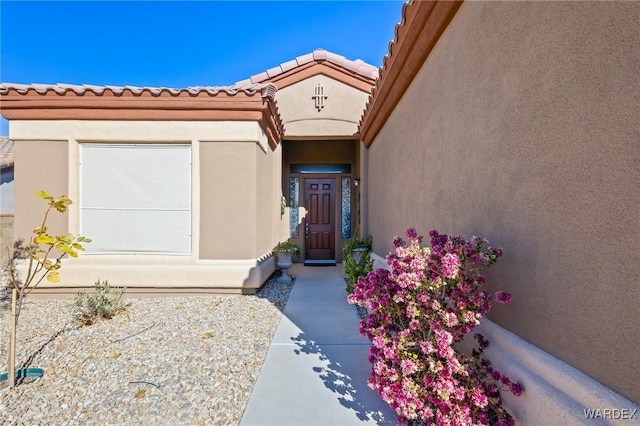 entrance to property with a tiled roof and stucco siding