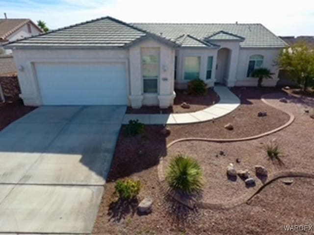 view of front of house with a garage, stucco siding, concrete driveway, and a tiled roof