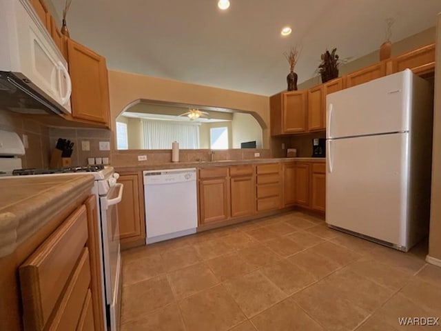 kitchen featuring ceiling fan, arched walkways, white appliances, light countertops, and backsplash