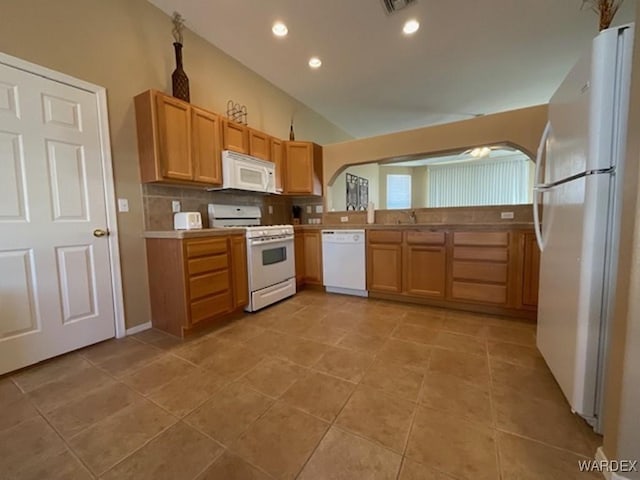 kitchen with arched walkways, light tile patterned floors, tasteful backsplash, lofted ceiling, and white appliances