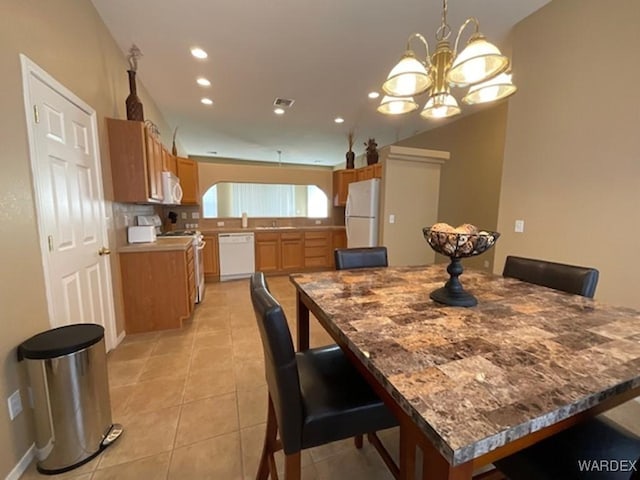 dining space with recessed lighting, a notable chandelier, and light tile patterned floors