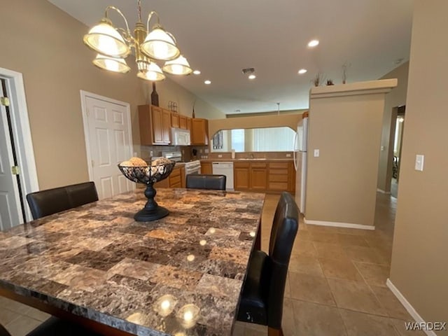 dining room featuring a chandelier, light tile patterned flooring, recessed lighting, baseboards, and vaulted ceiling