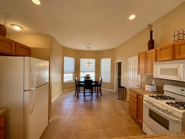 kitchen with pendant lighting, light countertops, backsplash, light tile patterned flooring, and white appliances