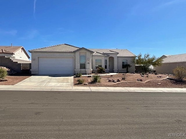 view of front of house with a garage, a tiled roof, concrete driveway, and stucco siding