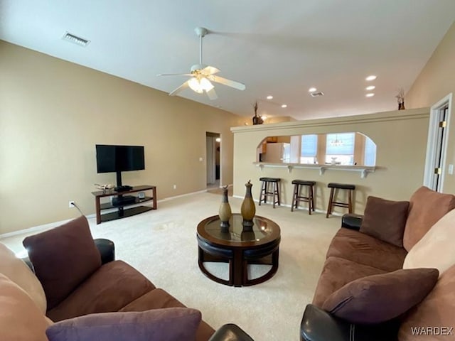 living area with light colored carpet, visible vents, vaulted ceiling, and baseboards