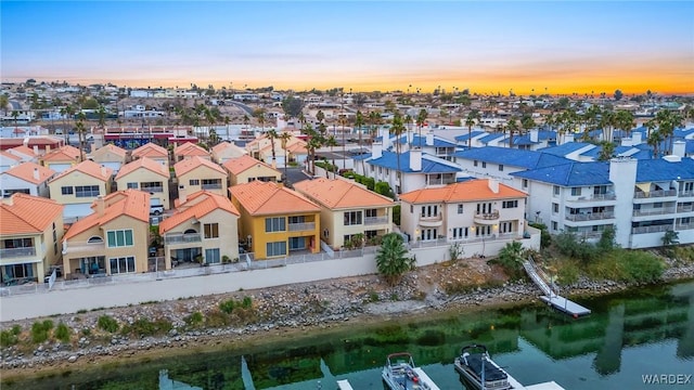 aerial view at dusk with a water view and a residential view