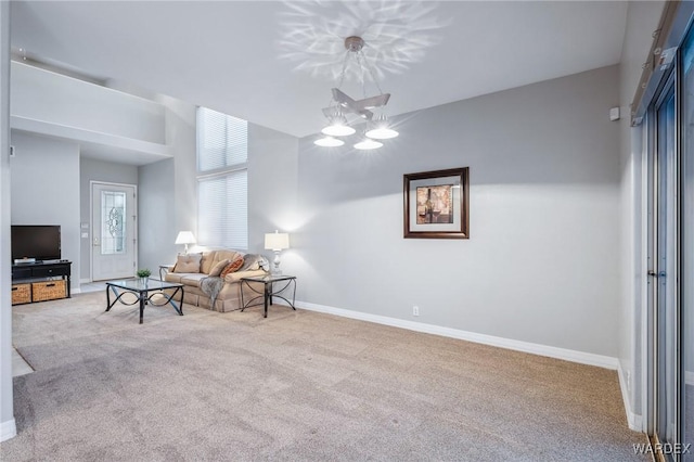 living room with light colored carpet, a notable chandelier, and baseboards