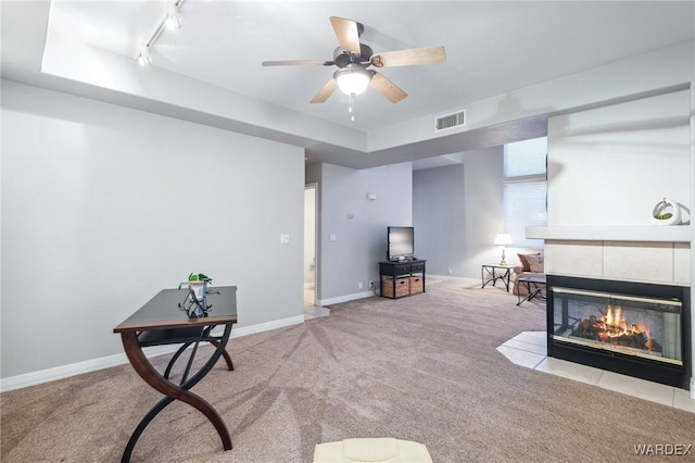 interior space featuring baseboards, a tile fireplace, visible vents, and light colored carpet