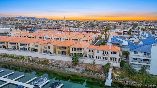 aerial view at dusk with a water view and a residential view