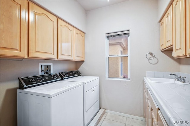 laundry room with cabinet space, baseboards, washer and clothes dryer, a sink, and light tile patterned flooring