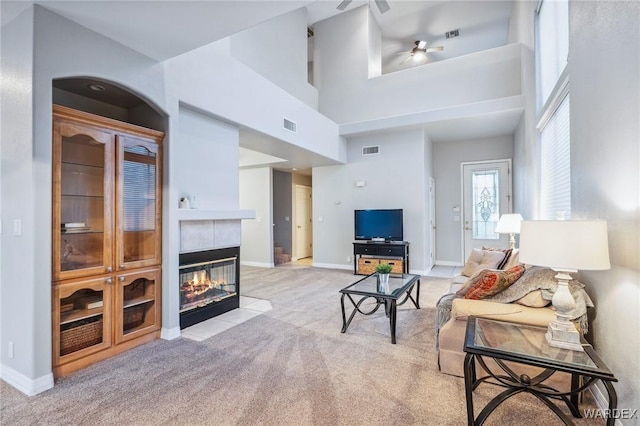 living area with baseboards, a tile fireplace, visible vents, and light colored carpet