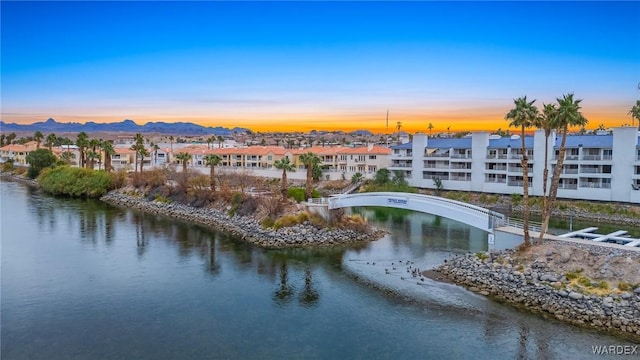 aerial view at dusk featuring a residential view and a water view