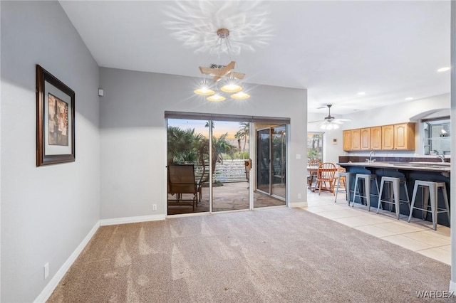 unfurnished living room featuring light tile patterned floors, baseboards, light colored carpet, a sink, and recessed lighting