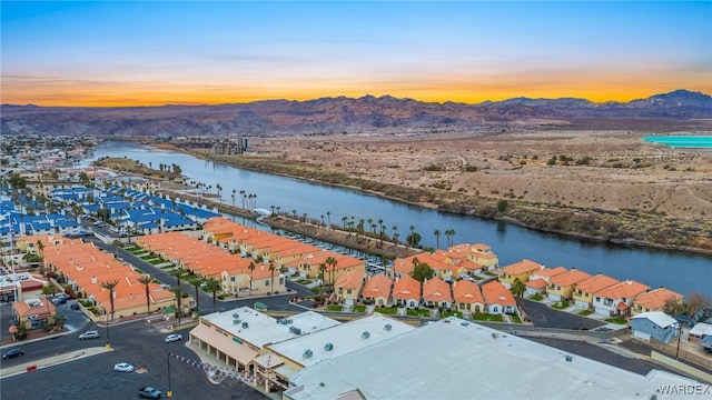 aerial view at dusk featuring a residential view and a water and mountain view