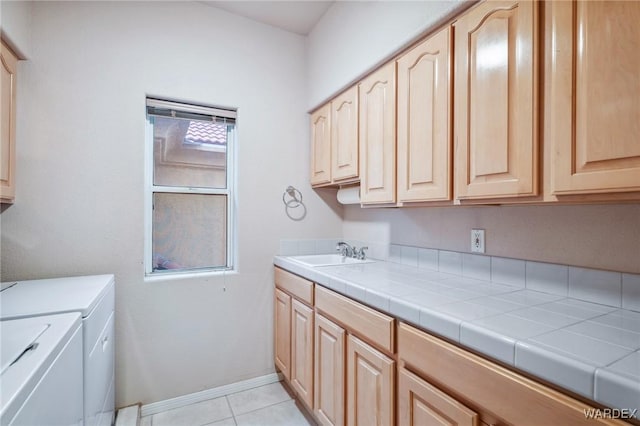 laundry room with light tile patterned floors, cabinet space, a sink, washer and dryer, and baseboards