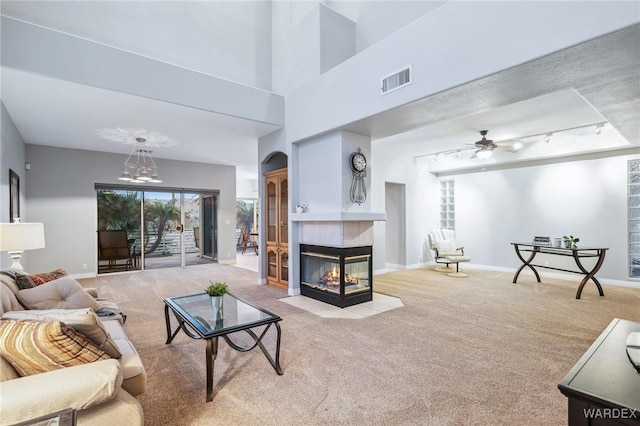 living area featuring ceiling fan, light carpet, visible vents, baseboards, and a tiled fireplace