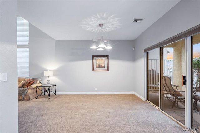 carpeted spare room featuring a chandelier, visible vents, and baseboards