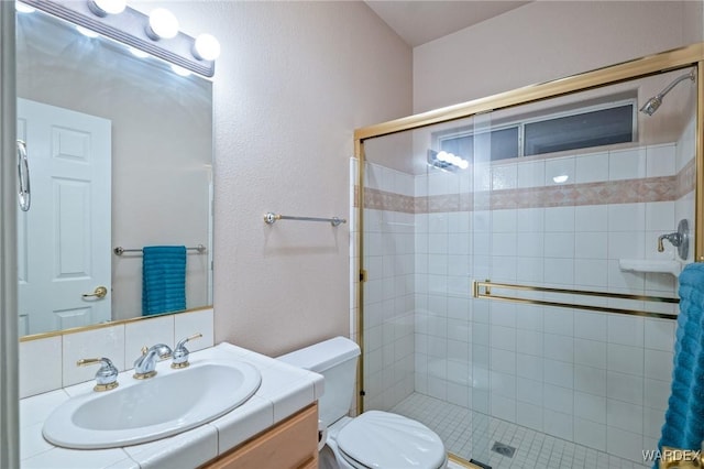 bathroom with a stall shower, vanity, and toilet