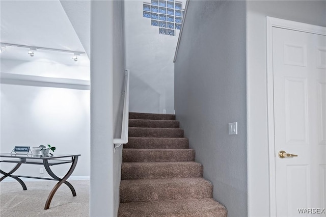 staircase with carpet floors and rail lighting