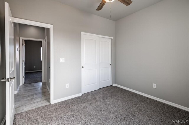 unfurnished bedroom with ceiling fan, a closet, carpet, and baseboards