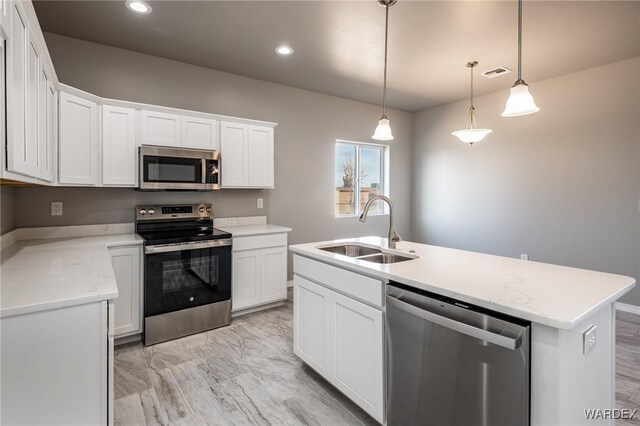 kitchen featuring a sink, white cabinetry, hanging light fixtures, appliances with stainless steel finishes, and an island with sink