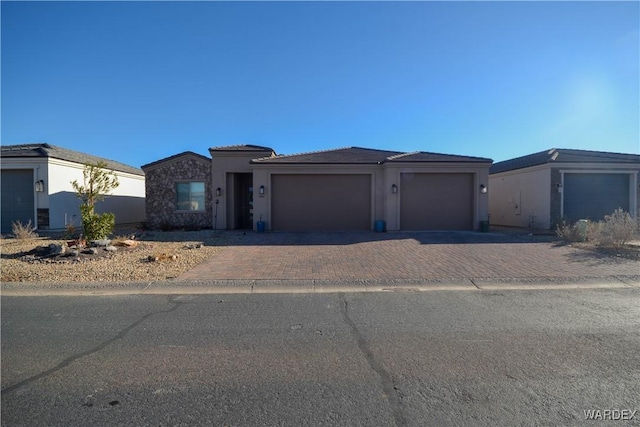 view of front facade with a garage, stone siding, and decorative driveway