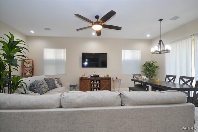 living room featuring a healthy amount of sunlight, ceiling fan with notable chandelier, visible vents, and recessed lighting