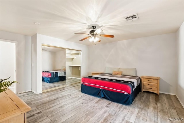 bedroom with a closet, visible vents, ceiling fan, wood finished floors, and baseboards