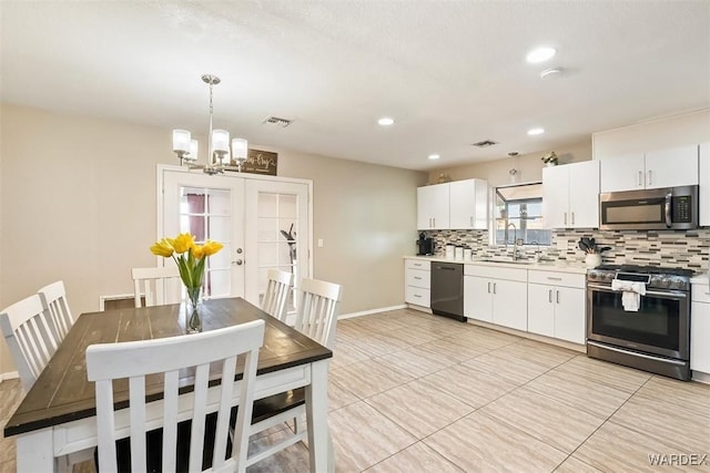 kitchen with light countertops, visible vents, decorative backsplash, appliances with stainless steel finishes, and white cabinetry