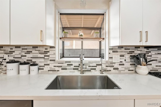 kitchen with light stone countertops, white cabinetry, and decorative backsplash