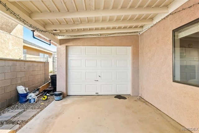 garage featuring fence and concrete driveway