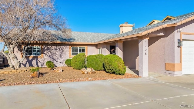 view of front of house with a chimney, an attached garage, and stucco siding