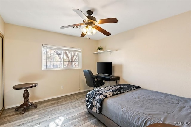 bedroom featuring a ceiling fan, visible vents, baseboards, and wood finished floors