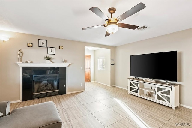 unfurnished living room with visible vents, baseboards, a glass covered fireplace, ceiling fan, and tile patterned flooring